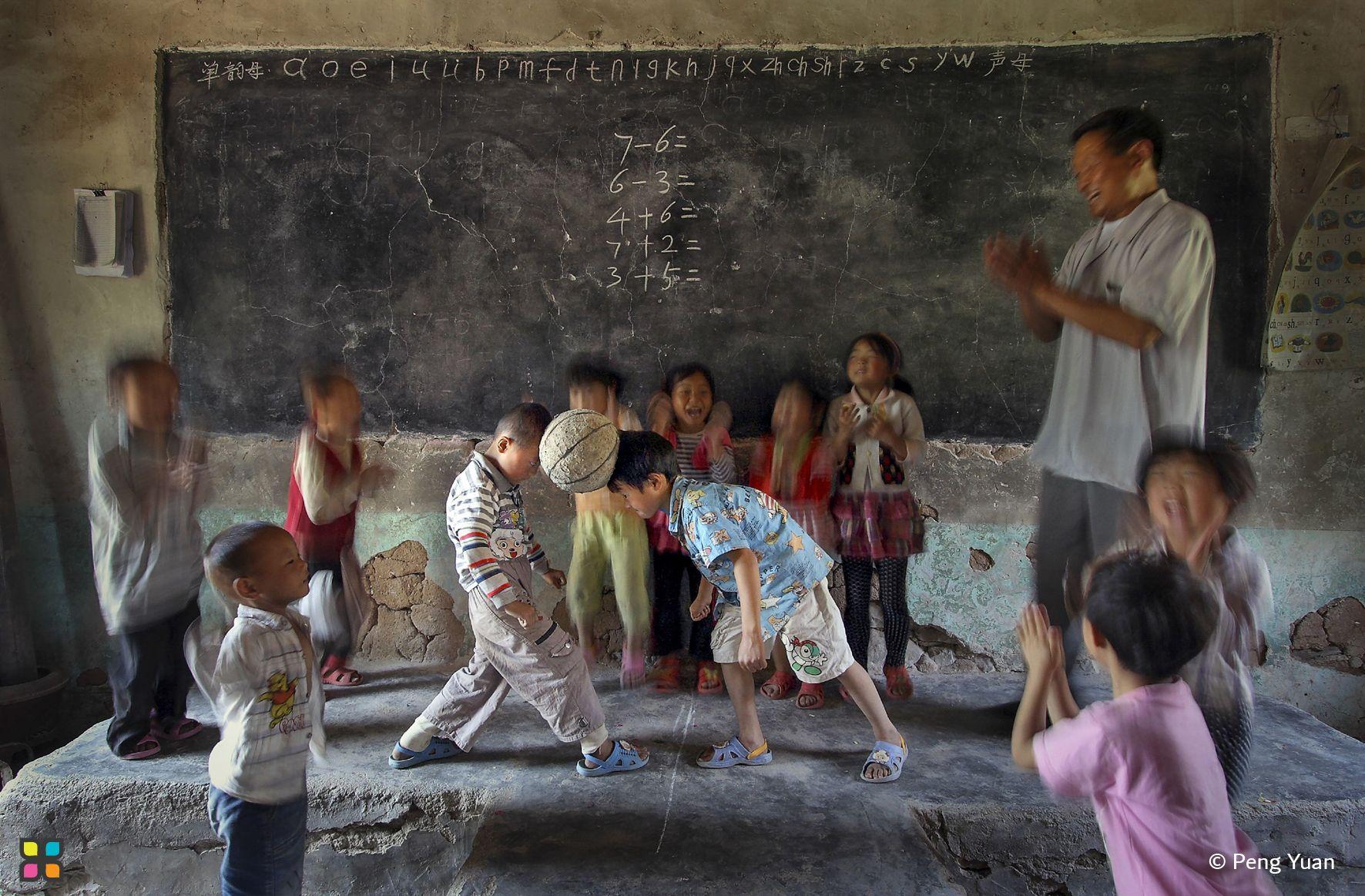 A playful moment erupts in a classroom as two boys play ball during a break in their studies.
Photographer: Peng Yuan   Location: China