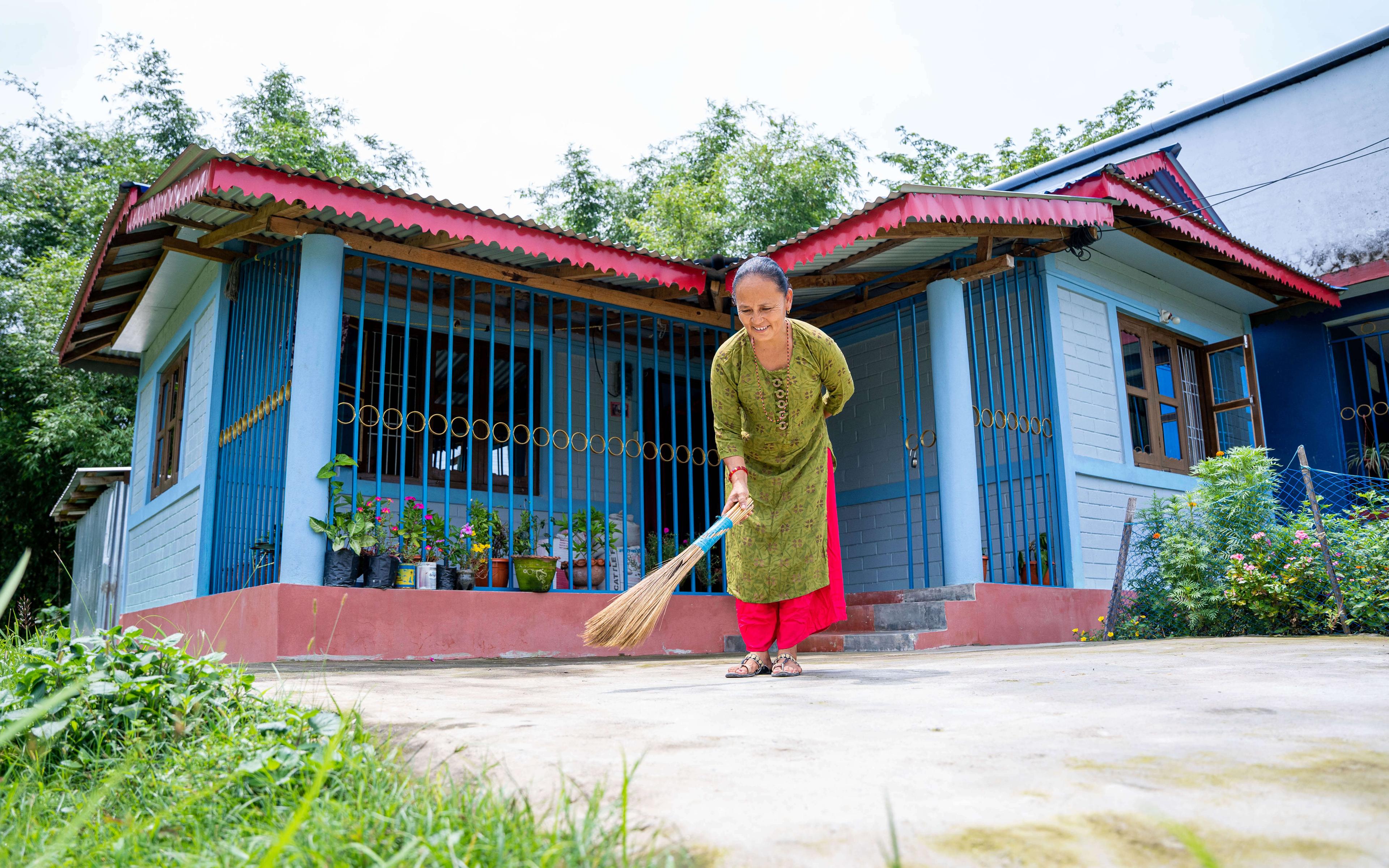 A happy homeowner in Nepal sweeps the front walk of her home made from Build Up Nepal’s eco-bricks.
Photographer: Rashik Maharjan