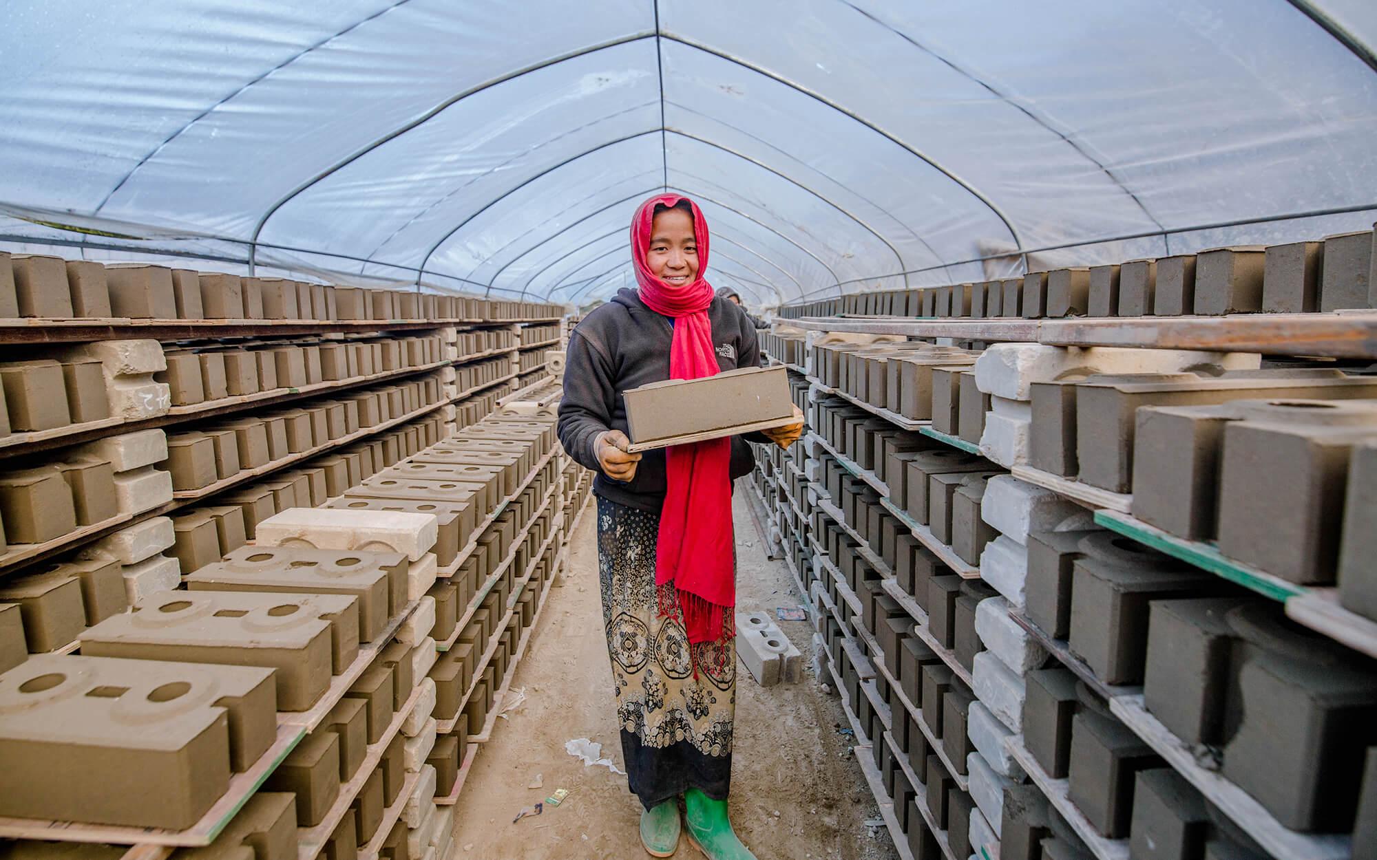 A woman stacks cured bricks for Build Up Nepal. 
Photographer: Rashik Maharjan