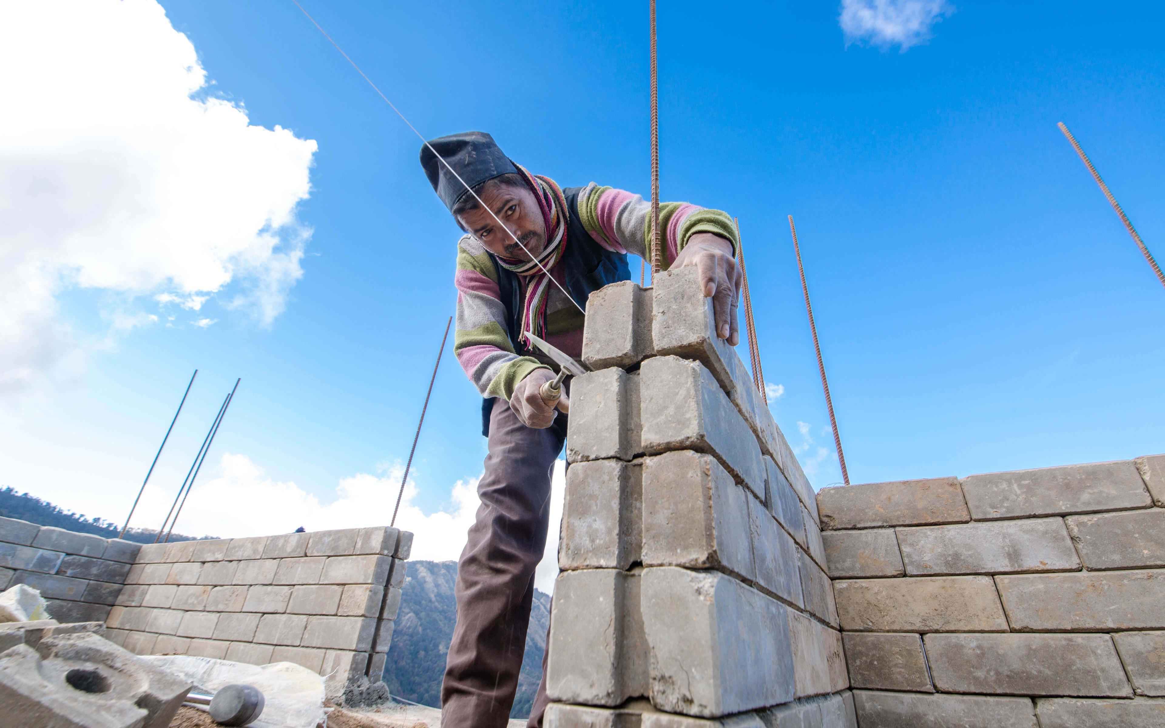 A labourer helps to build a disaster-resilient home with Build Up Nepal’s eco bricks. 
Photographer: Rashik Maharjan