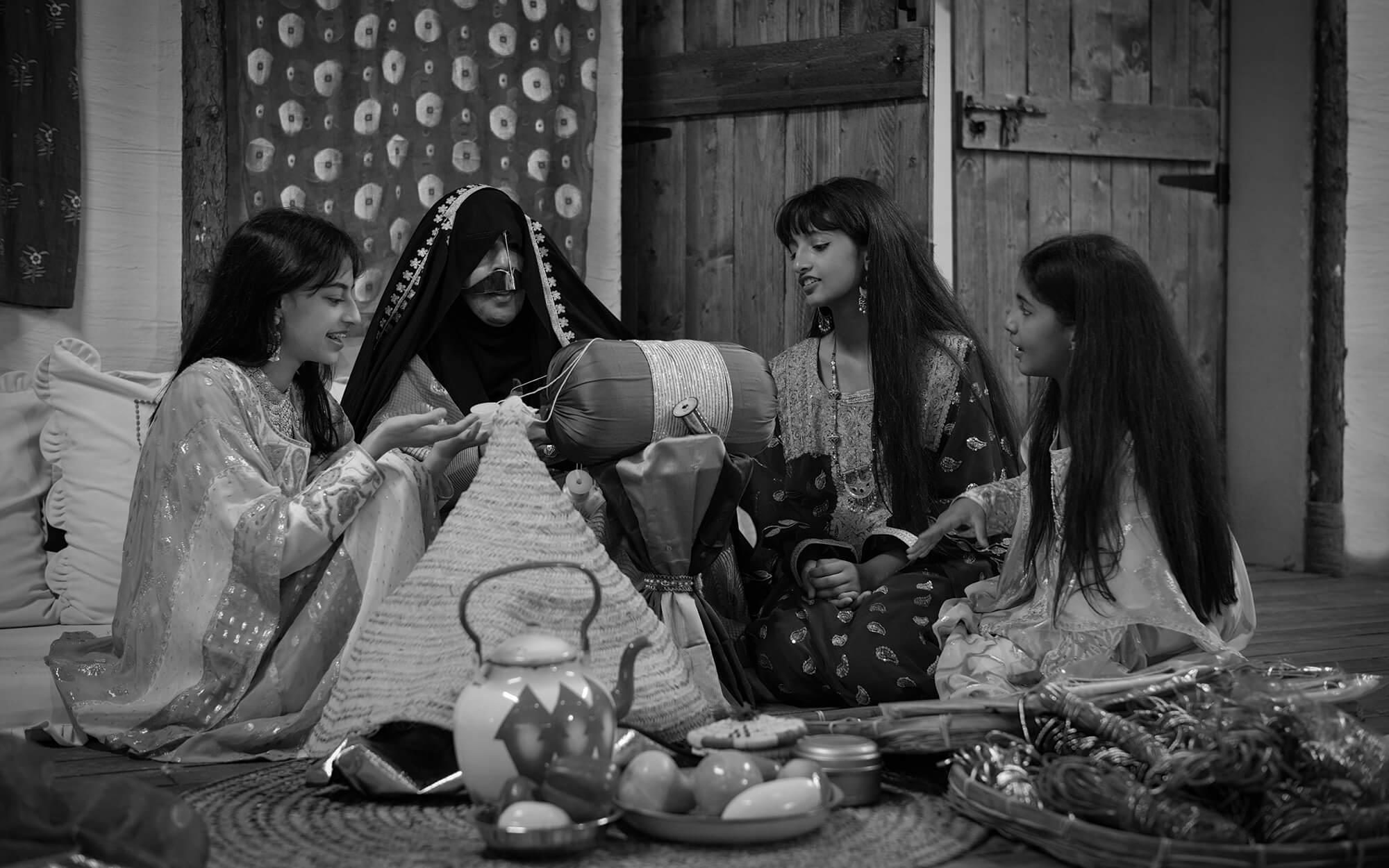 مجموعة من الفتيات مرتديات الأزياء الإماراتية، يجلسن معًا في جو تراثي دافئ يشاركن في حرفة يدوية، المشهد يعكس مظاهر الحياة الاجتماعية وأجواء الماضي.
المصدر: فاطمة الموسى